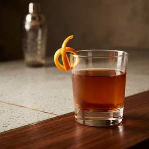 An image of the Four in Hand cocktail submitted by Toby that contains Bourbon, Apple Brandy, Smith & Cross, Green Chartreuse, Cinnamon Syrup, Vanilla Syrup and Orange