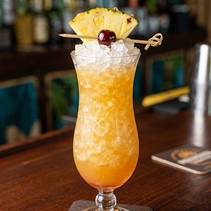 An image of the Piña Colada cocktail submitted by Toby that contains Pineapple Juice, Coco Lopez, White Rum, Dark Rum, Cream, Angostura Bitters, Pineapple and Cocktail Cherry